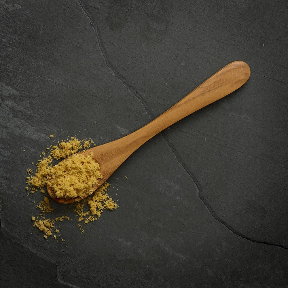 A wooden spoon of crumbled freeze dried fish topper on slate