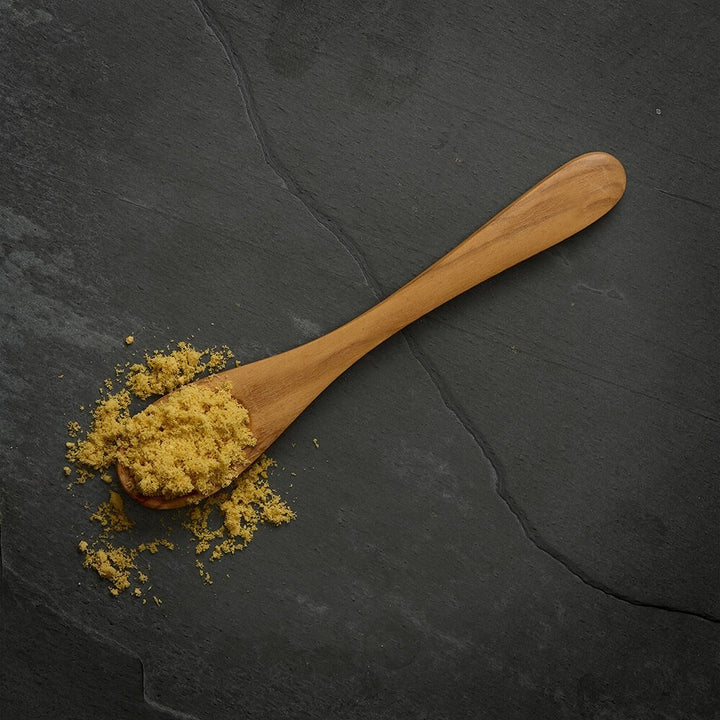 A wooden spoon of crumbled freeze dried fish topper on slate
